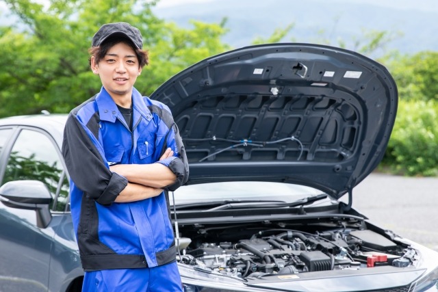腕を組んでこちらを見る車屋の作業員